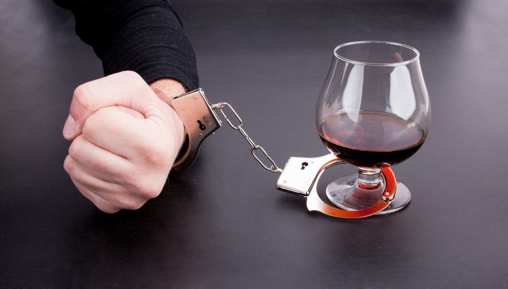 Алкохолизъм, ръка в белезници и чаша коняк
